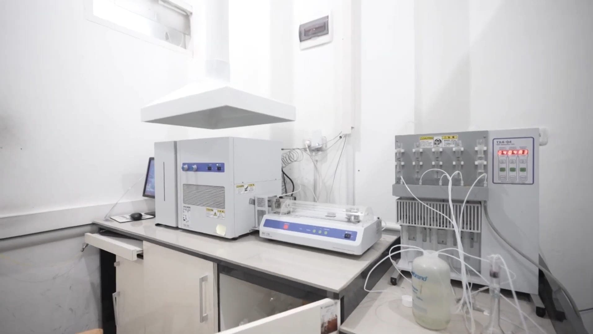 Instrumen analisis di meja laboratorium di bawah tudung ekstraksi.